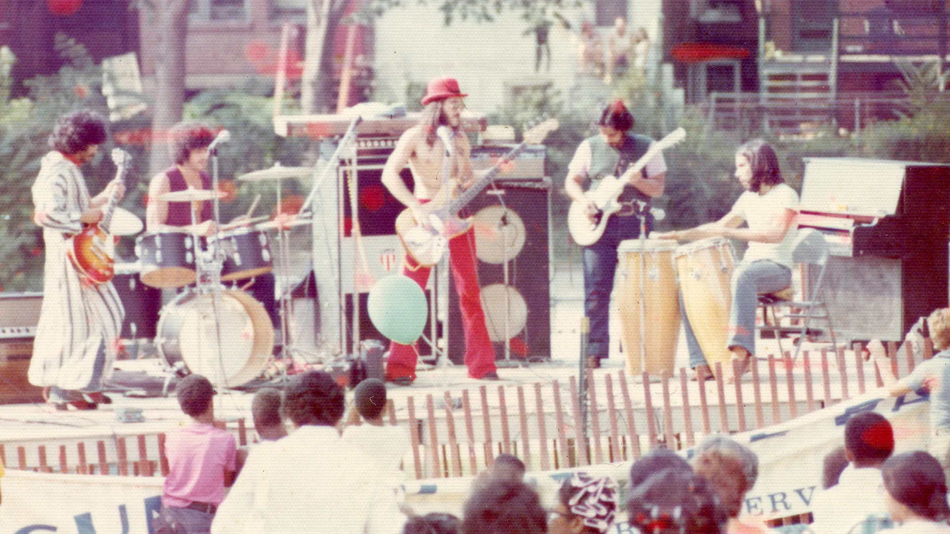 Band performing outdoors with instruments and audience