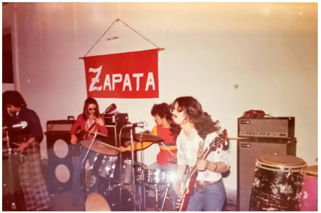 Color photograph of Zapata performing indoors with a red Zapata banner hanging behind the stage