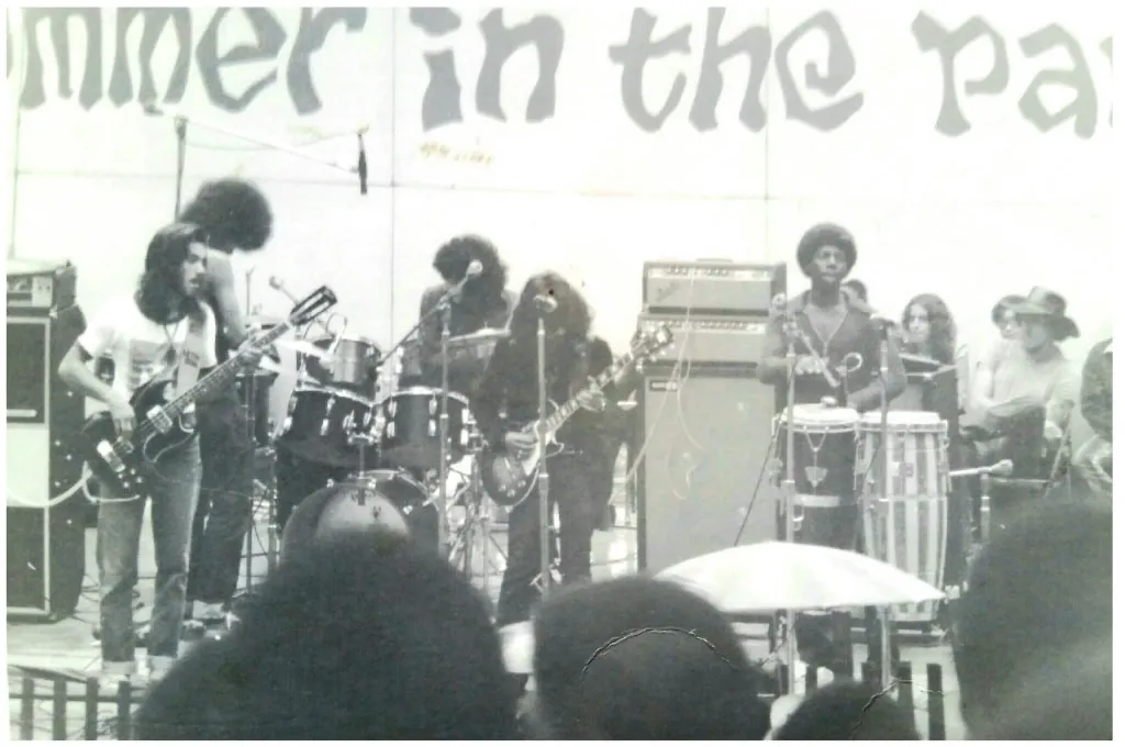 Black and white live performance photo of Zapata playing onstage in front of a crowd